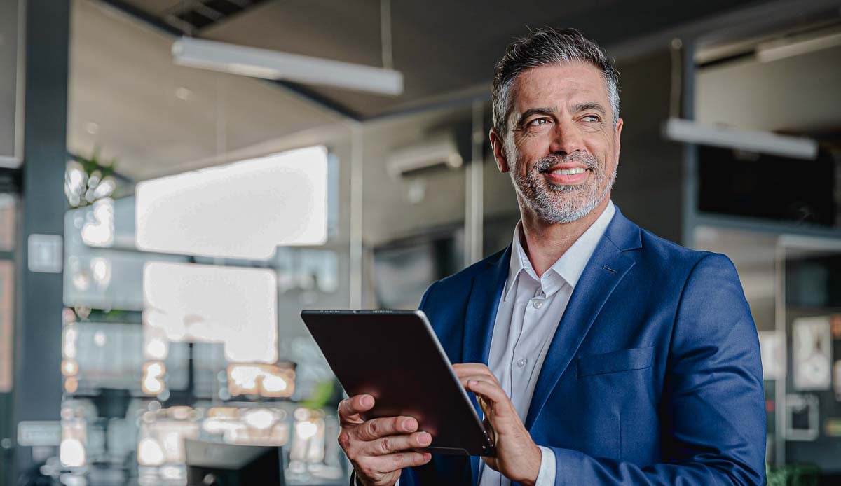 Imagem de executivo da Allianz utilizando um tablet e sorrindo
