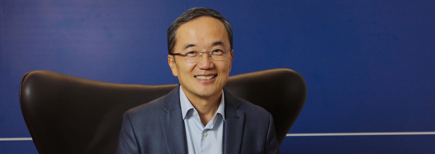 Diretor de Massificados sentado na poltrona diante de painel azul com a marca Allianz ao fundo.