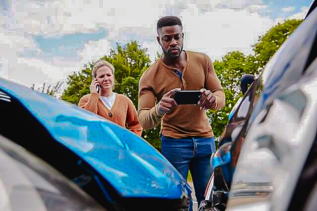 Imagem de duas pessoas tirando fotos após a colisão de veículos