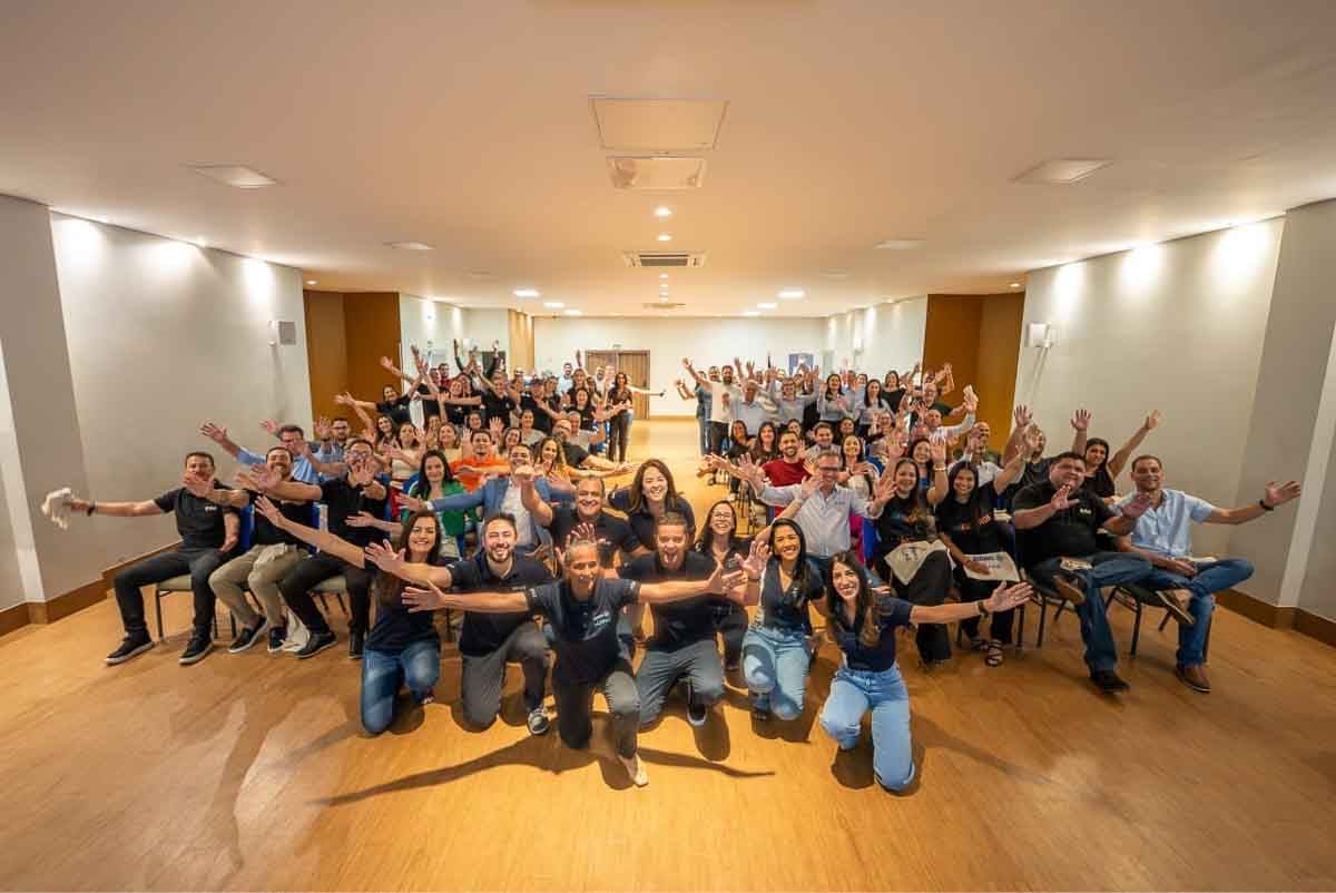  Pessoas com braços levantados em foto de treinamento da Allianz Seguros para ampliar a oferta de seguro Rural no Mato Grosso.