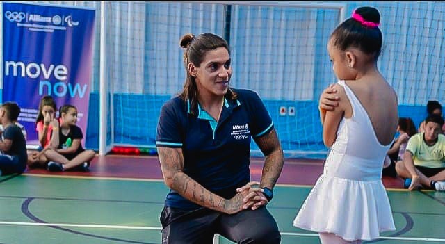 Foto da Ana Marcela Cunha conversando com uma criança bailarina