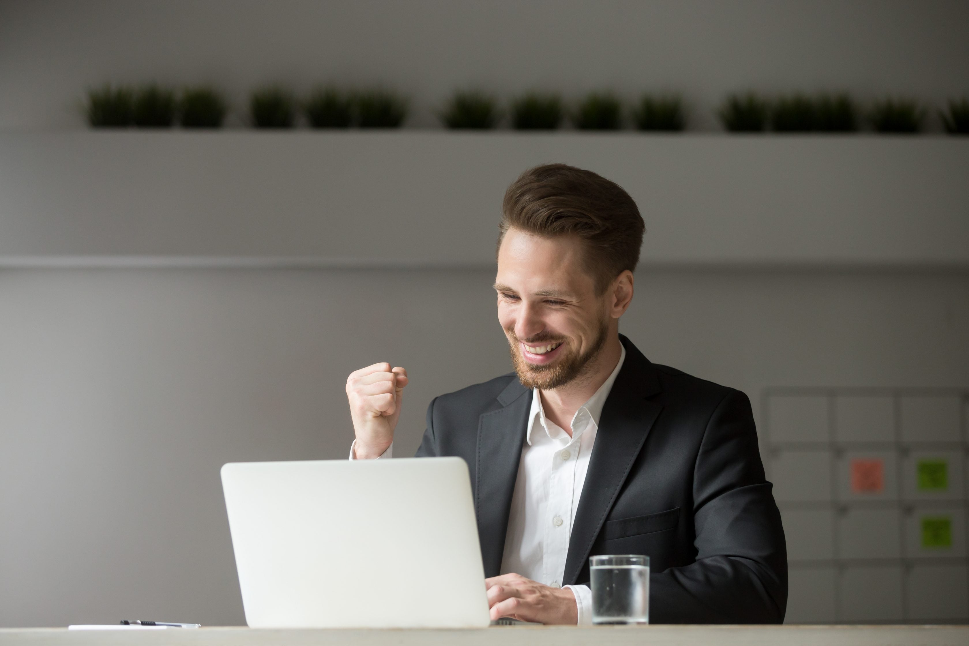 Imagem de corretor Allianz utilizando notebook e comemorando com punho cerrado