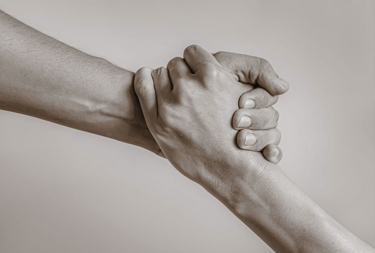 Pessoa segurando a mão de outra ajudando a levantar