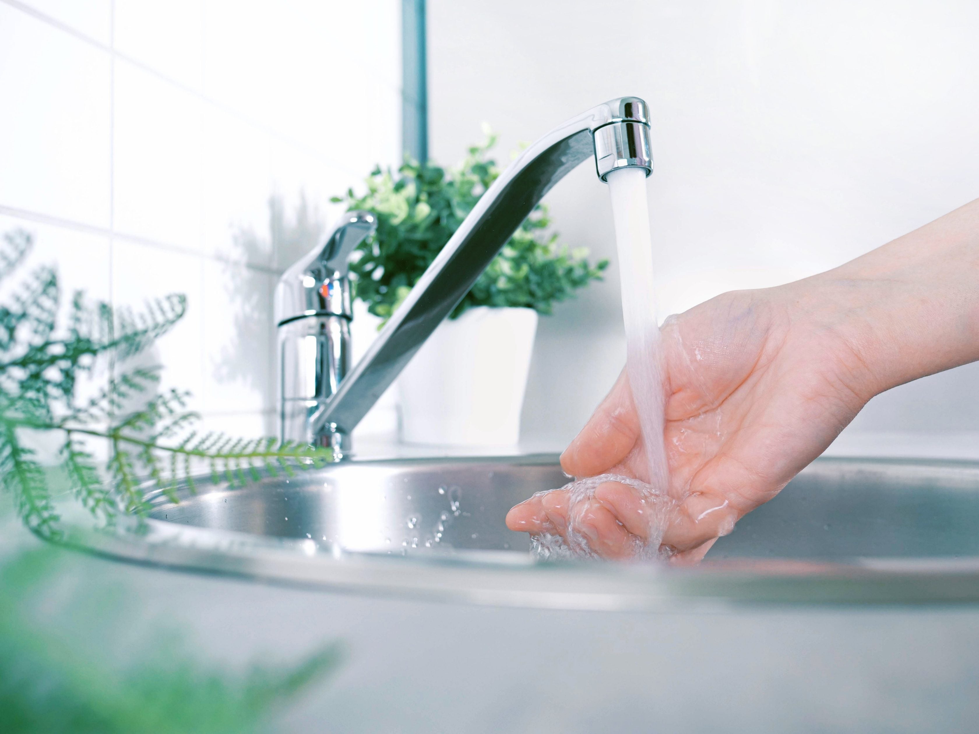 Imagem de uma pessoa lavando as mãos em uma torneira
