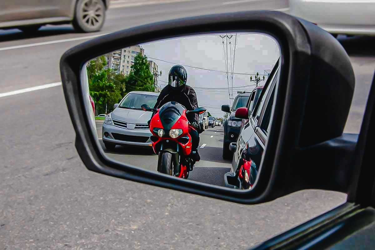Imagem de um motociclista sendo visto pelo retrovisor