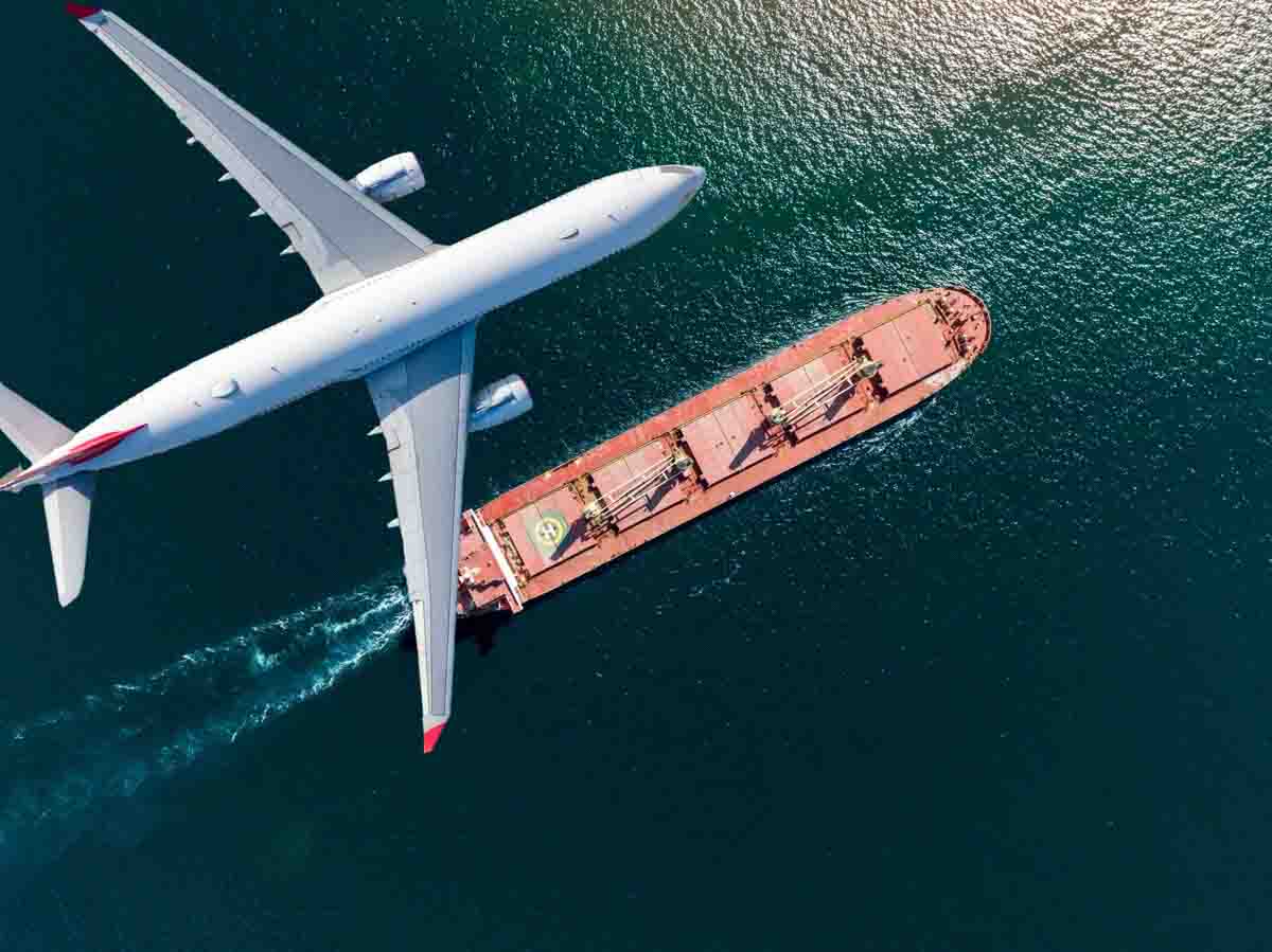 Imagem de um avião sobrevoando um navio cargueiro