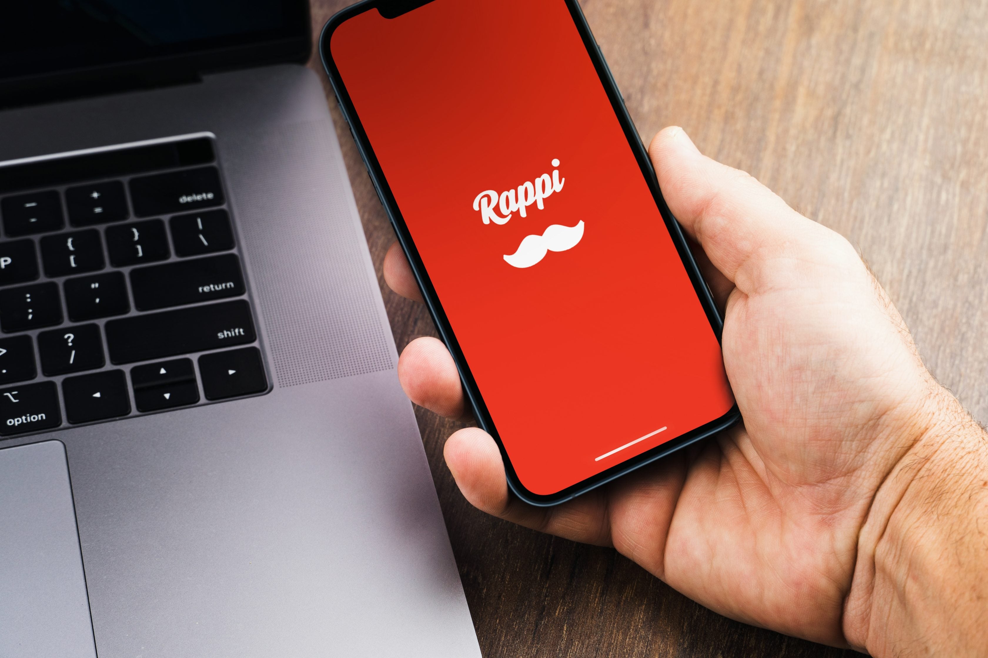 Pessoa segurando o celular com app da Rappi parceira da Allianz
