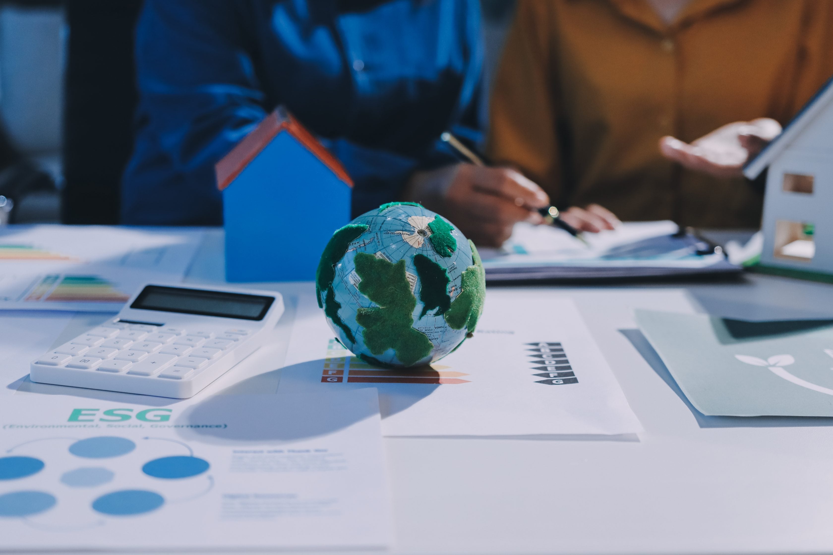 Imagem de um mapa mundi e uma calculadora com pessoas conversando ao fundo