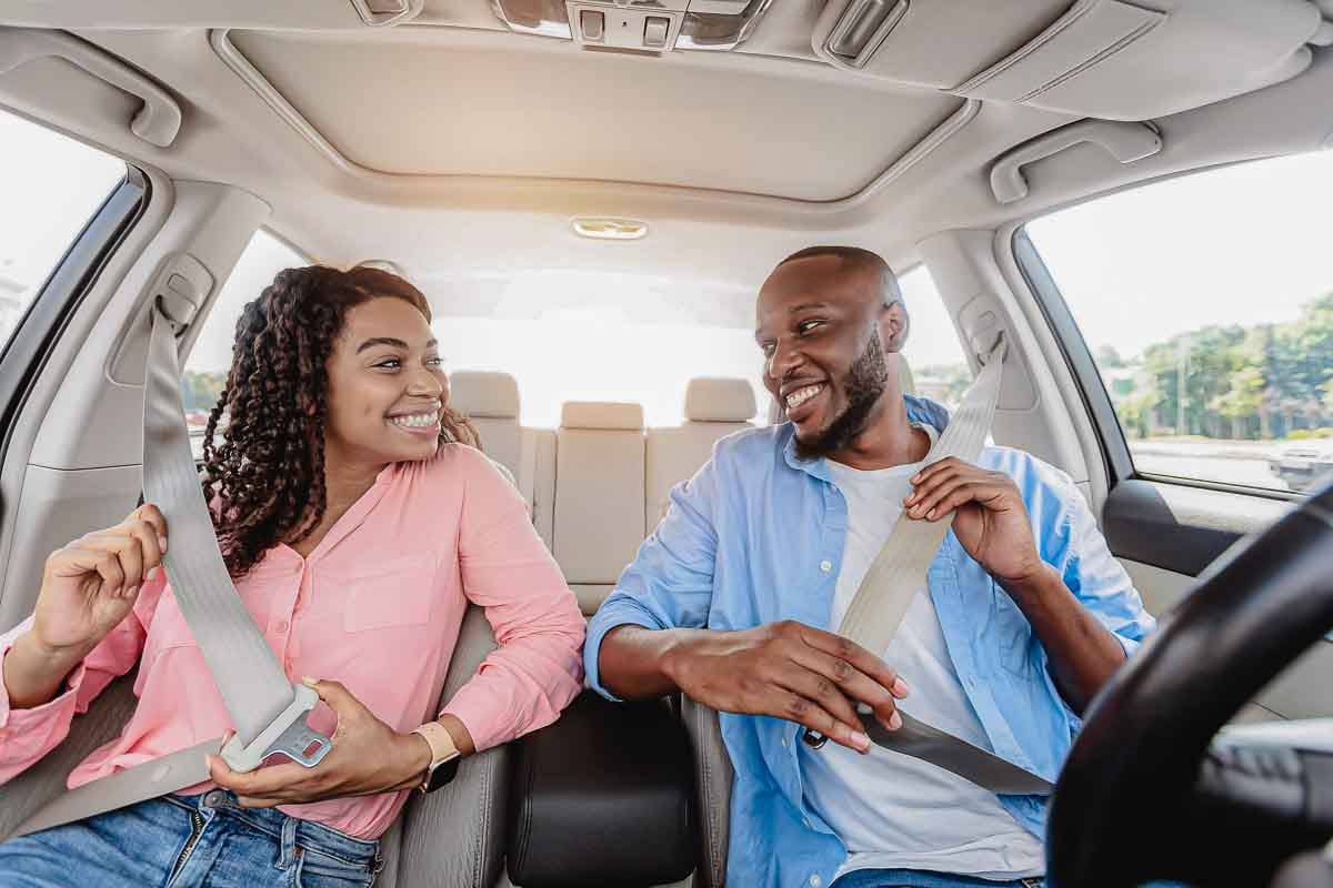 Imagem de um casal dentro de um automóvel sorrindo