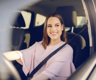 Imagem de uma mulher dirigindo seu automóvel e sorrindo