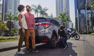 Imagem de um casal sendo socorrido pelo Seguro Allianz trocando pneu do veículo