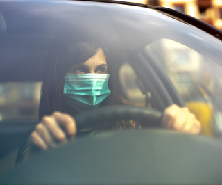 Imagem de uma mulher dirigindo seu automóvel de máscara