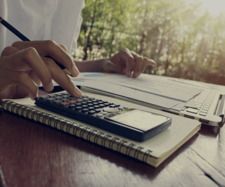 Pessoa utilizando uma calculadora para fazer cálculos e anotações