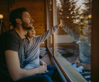 Pai e filho olhando para janela em uma casa feita de madeira