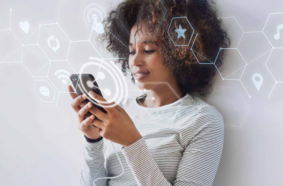 Mulher negra sorrindo e utilizando o celular com símbolos de tecnologia