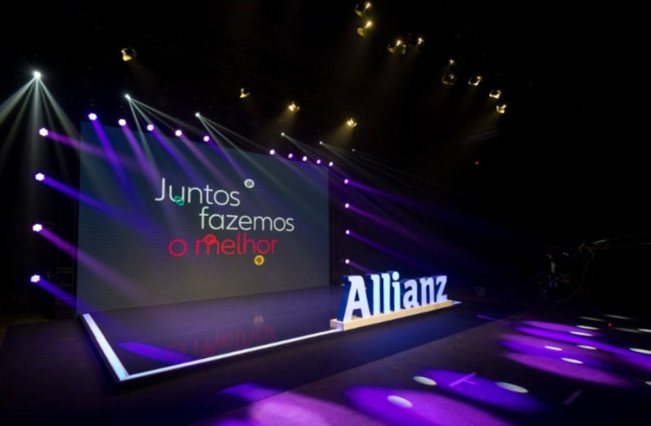Palco de evento corporativo da Allianz com telão e logotipo ilimunado.