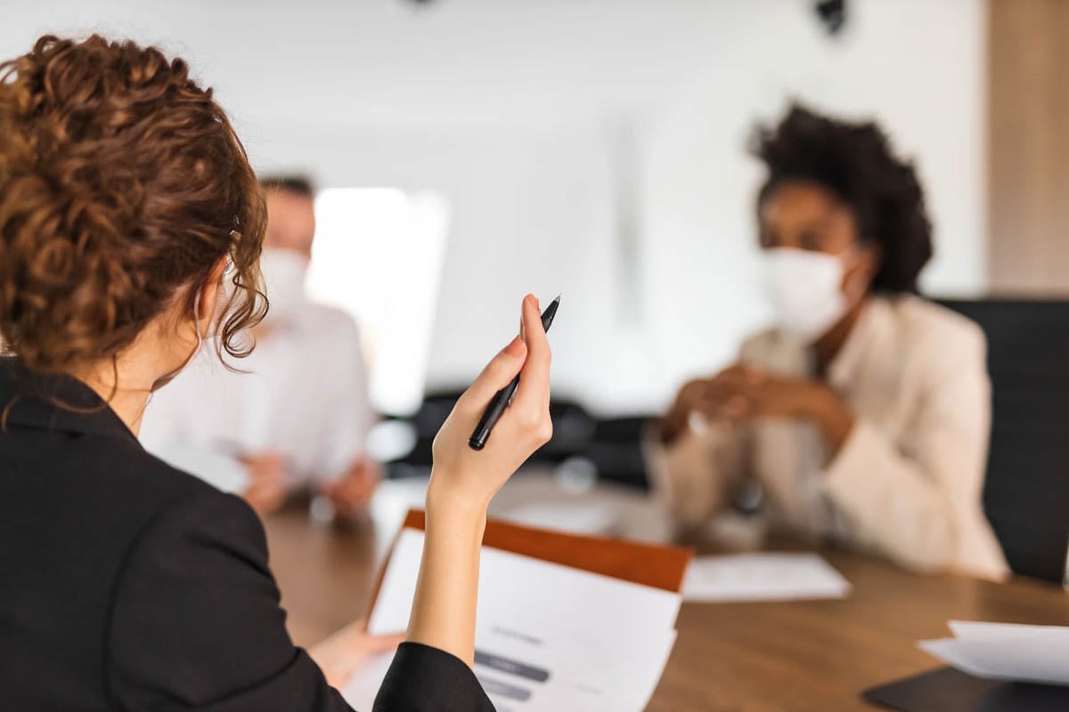 Diretoras da Allianz conversando sentadas em uma mesa e uma delas está segurando uma caneta