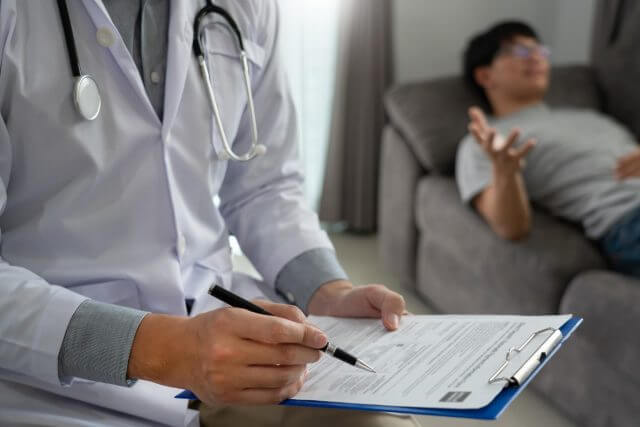 Médico preenchendo prancheta enquanto paciente relata seu caso