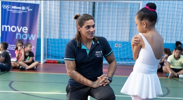 Ana Marcela Cunha ao lado de criança, durante uma visita ao projeto internacional da associação Allianz