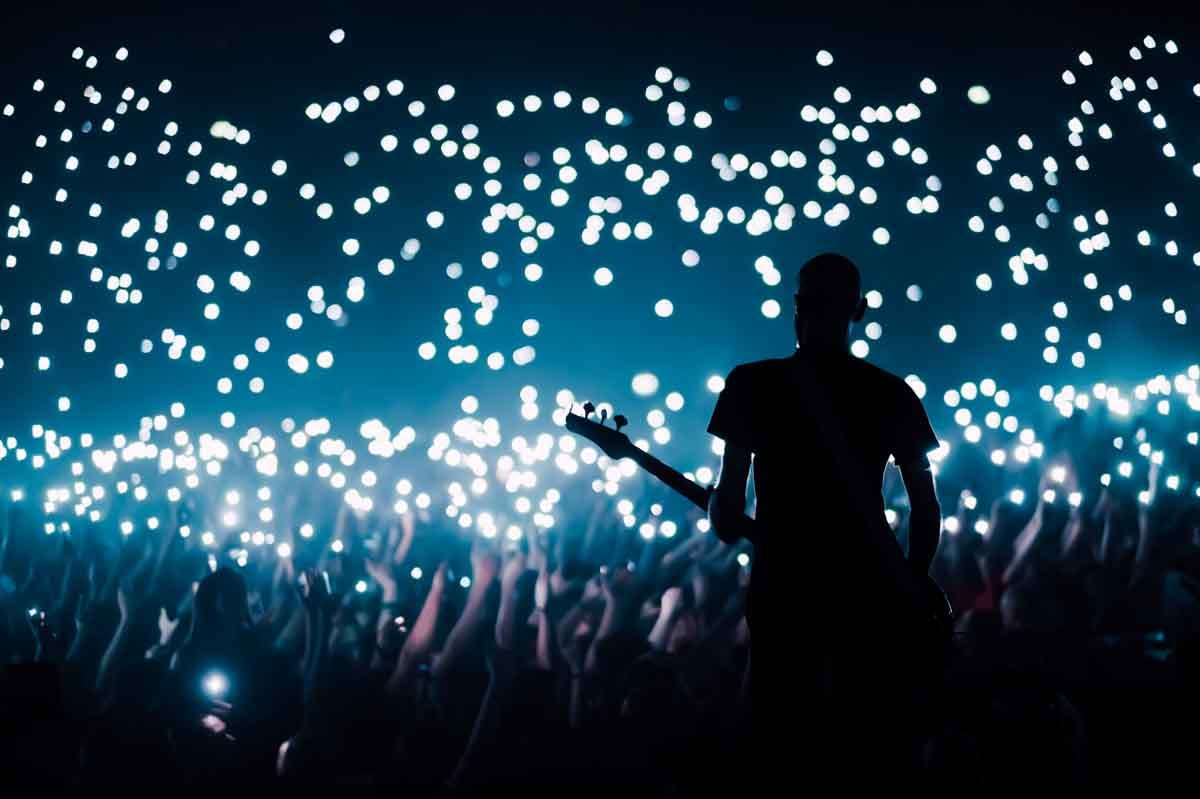 Pessoas reunidas em um show com vista para o guitarrista.