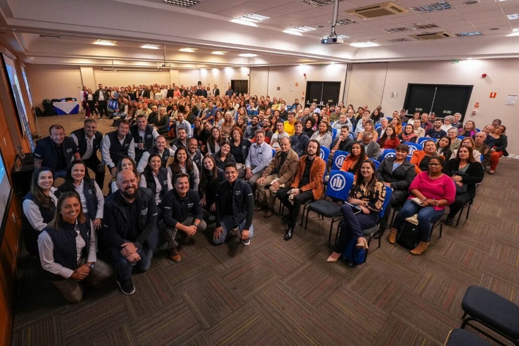 Grupo de corretores em auditório lotado durante treinamento.