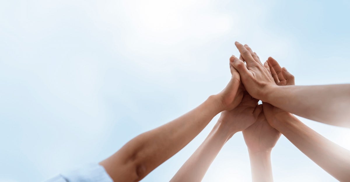 Foto em perspectiva de pessoas tocando as mãos em sinal de união.