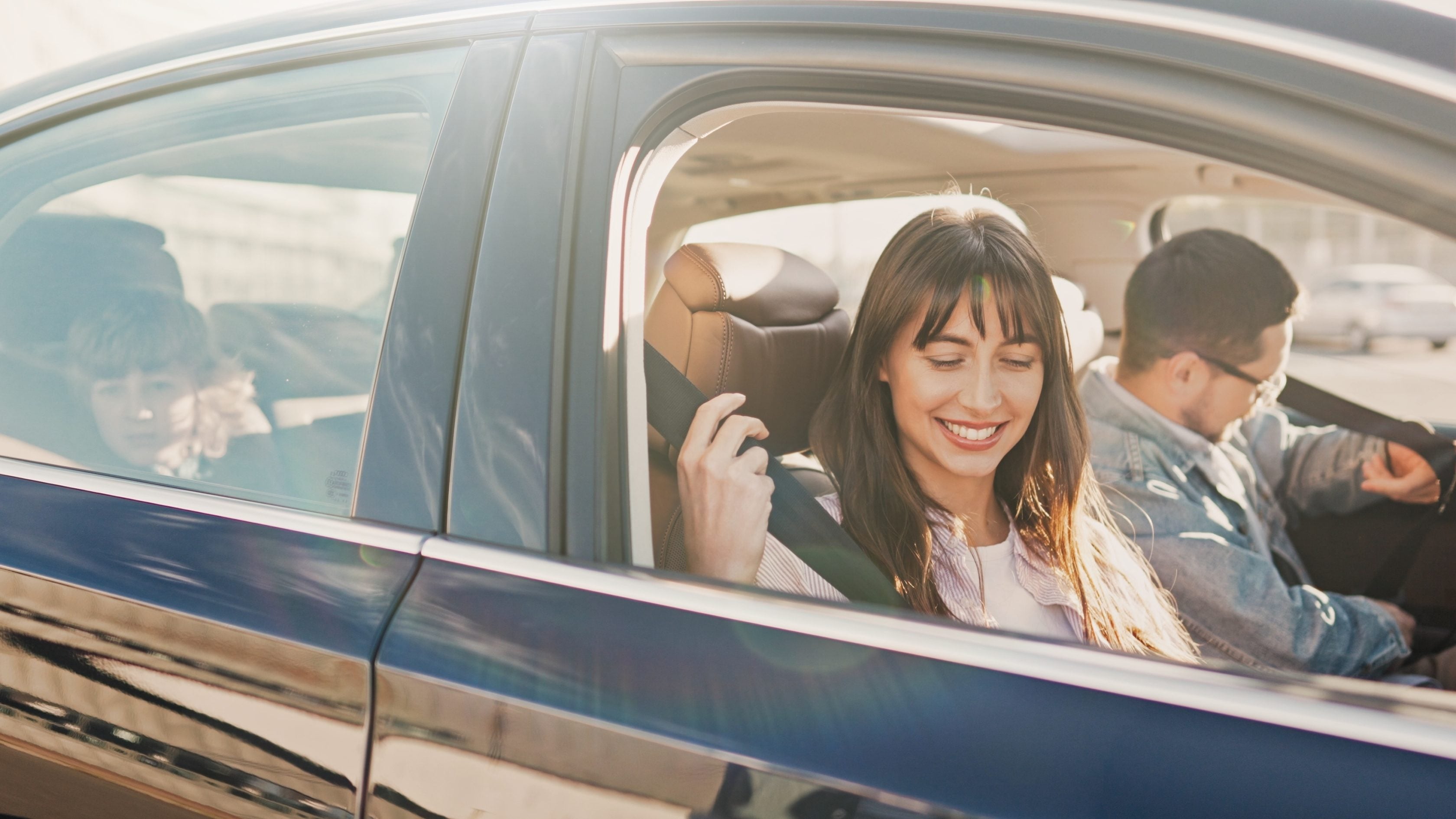 Familia sorridente dentro de carro em viagem.