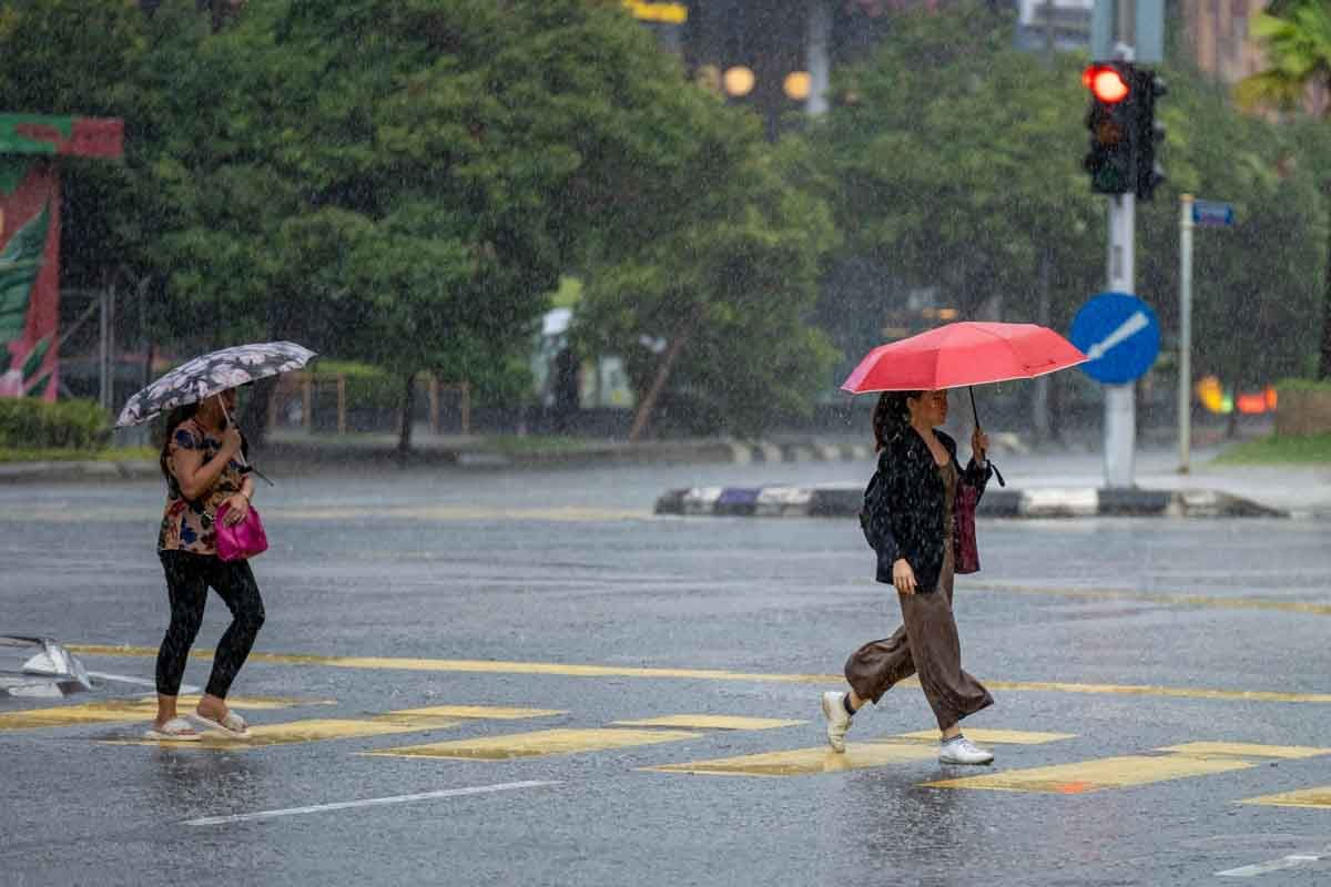 Duas mulheres usando guarda chuva na rua em clima de chuva.
