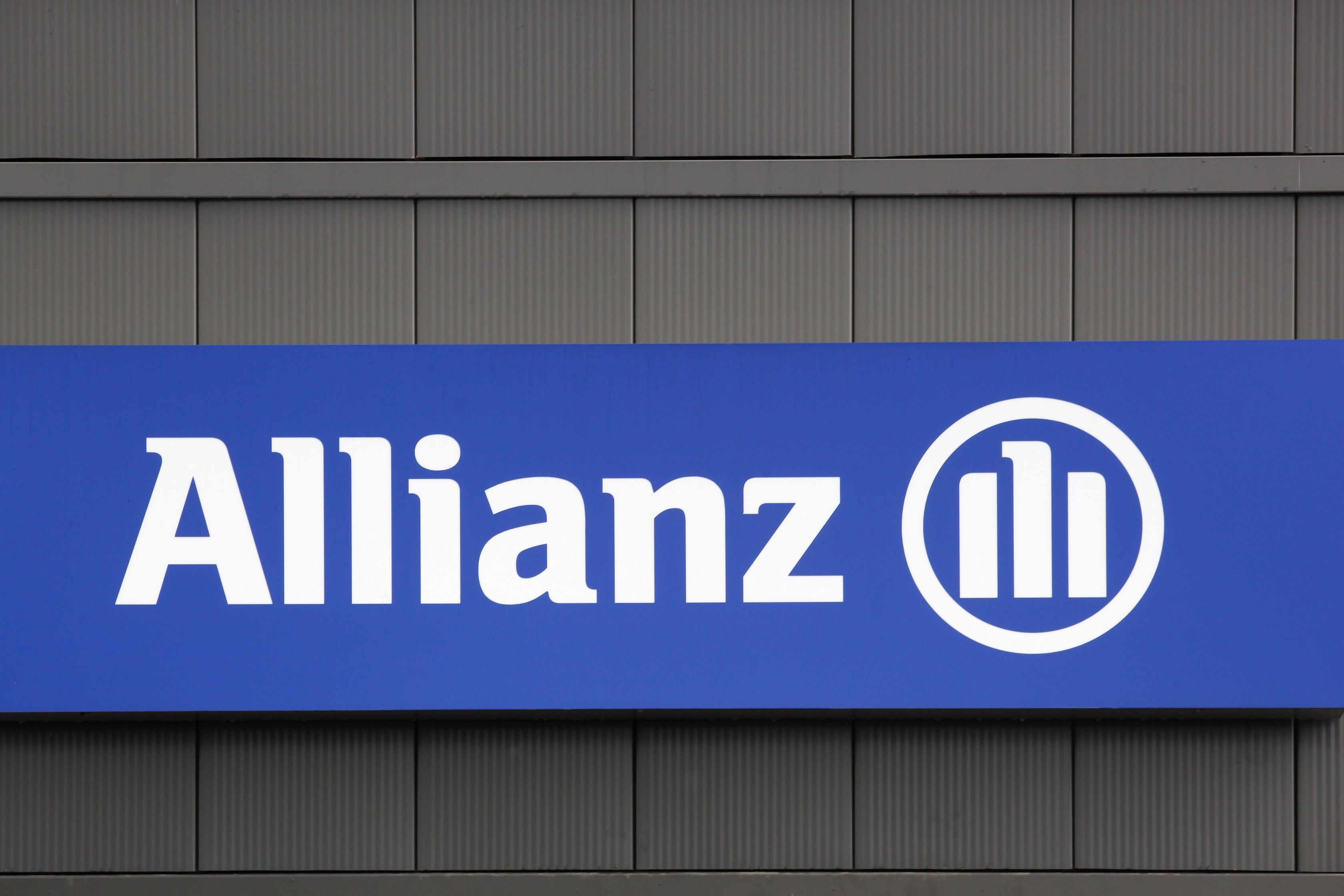 Logo da Allianz em placa azul instalada em parede.