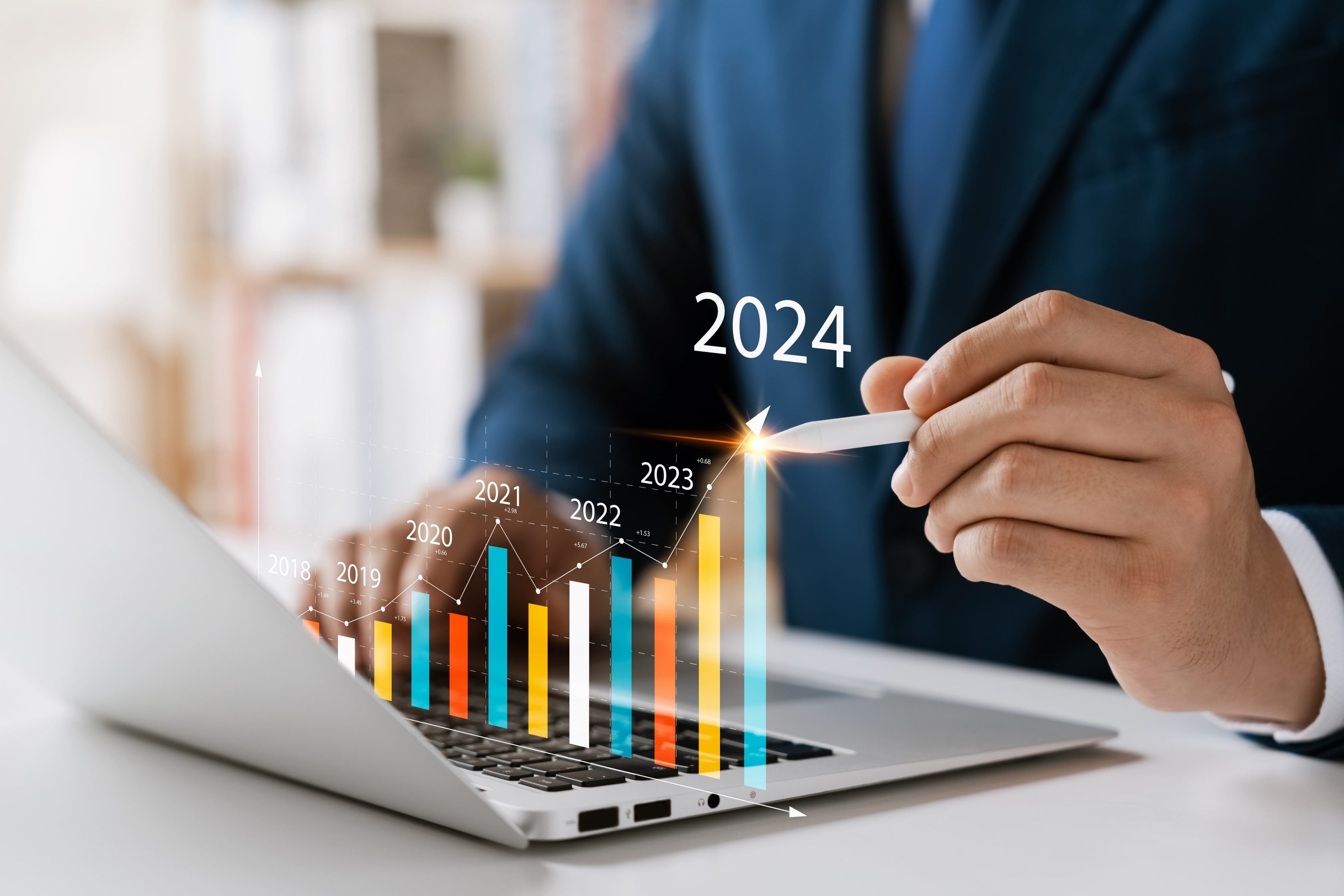 Homem usando notebook com gráfico digital flutuante apontando crescimento no ano de 2024.