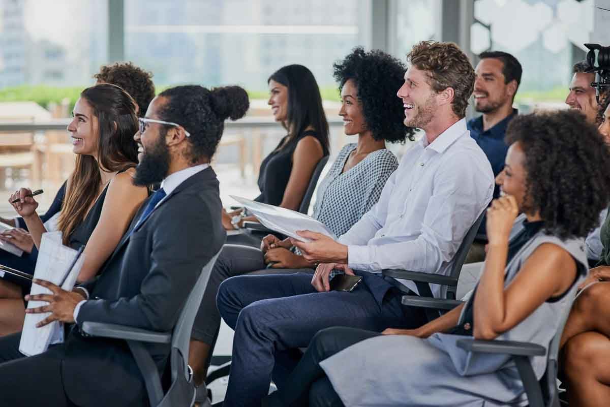 Grupo diverso de pessoas assistindo a uma palestra ou seminário.
