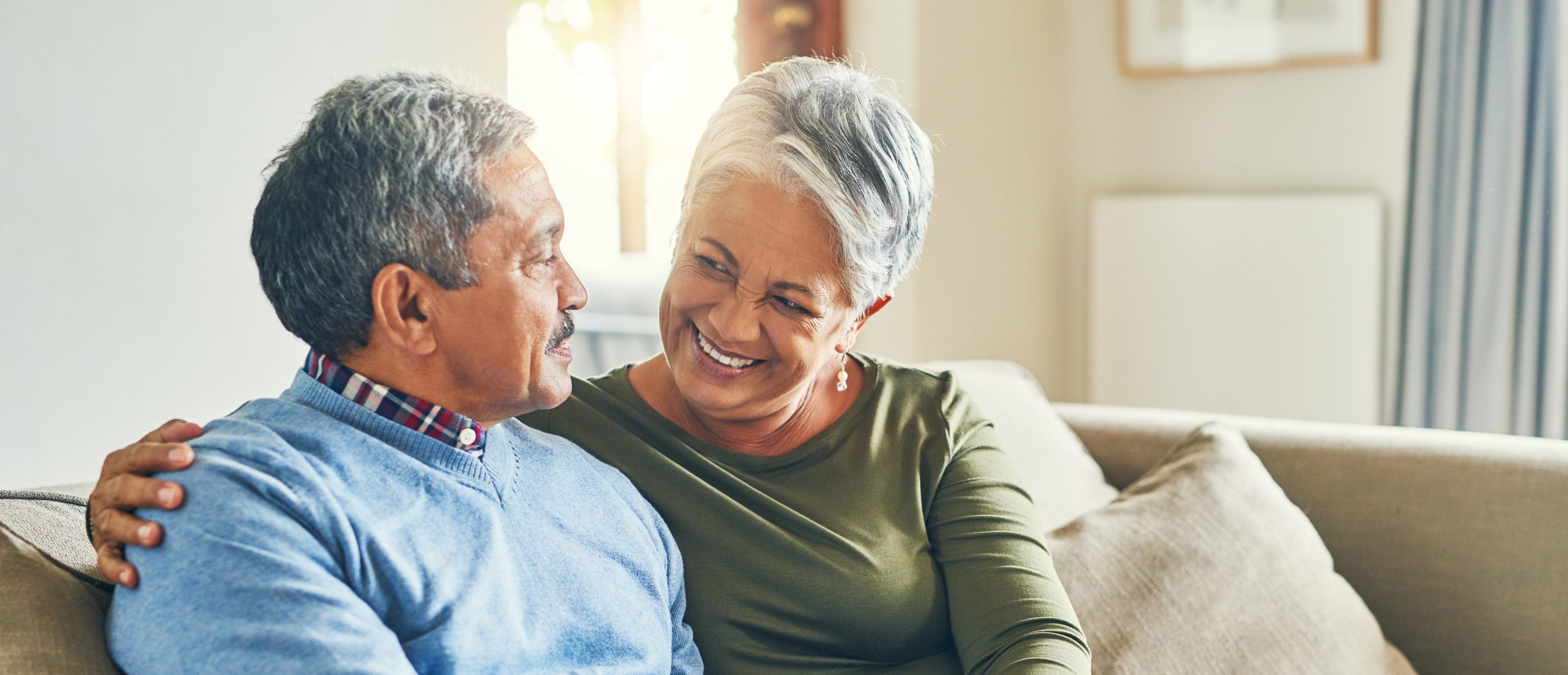 Casal de idosos sentados juntos no sofá.