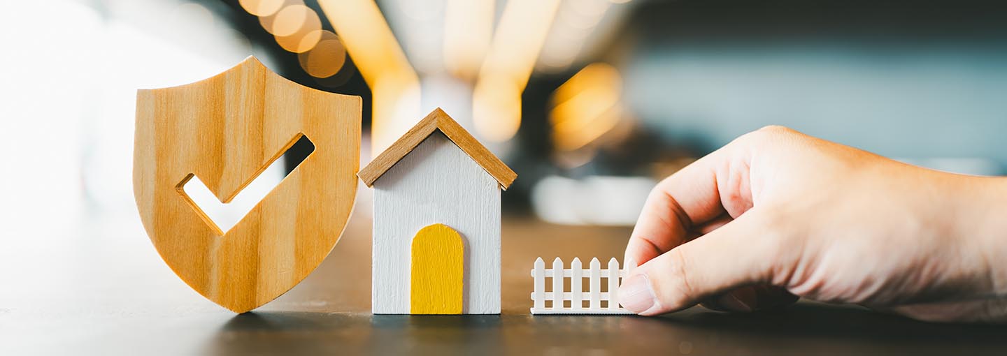 Miniaturas simbolizando proteção residencial e segurança.