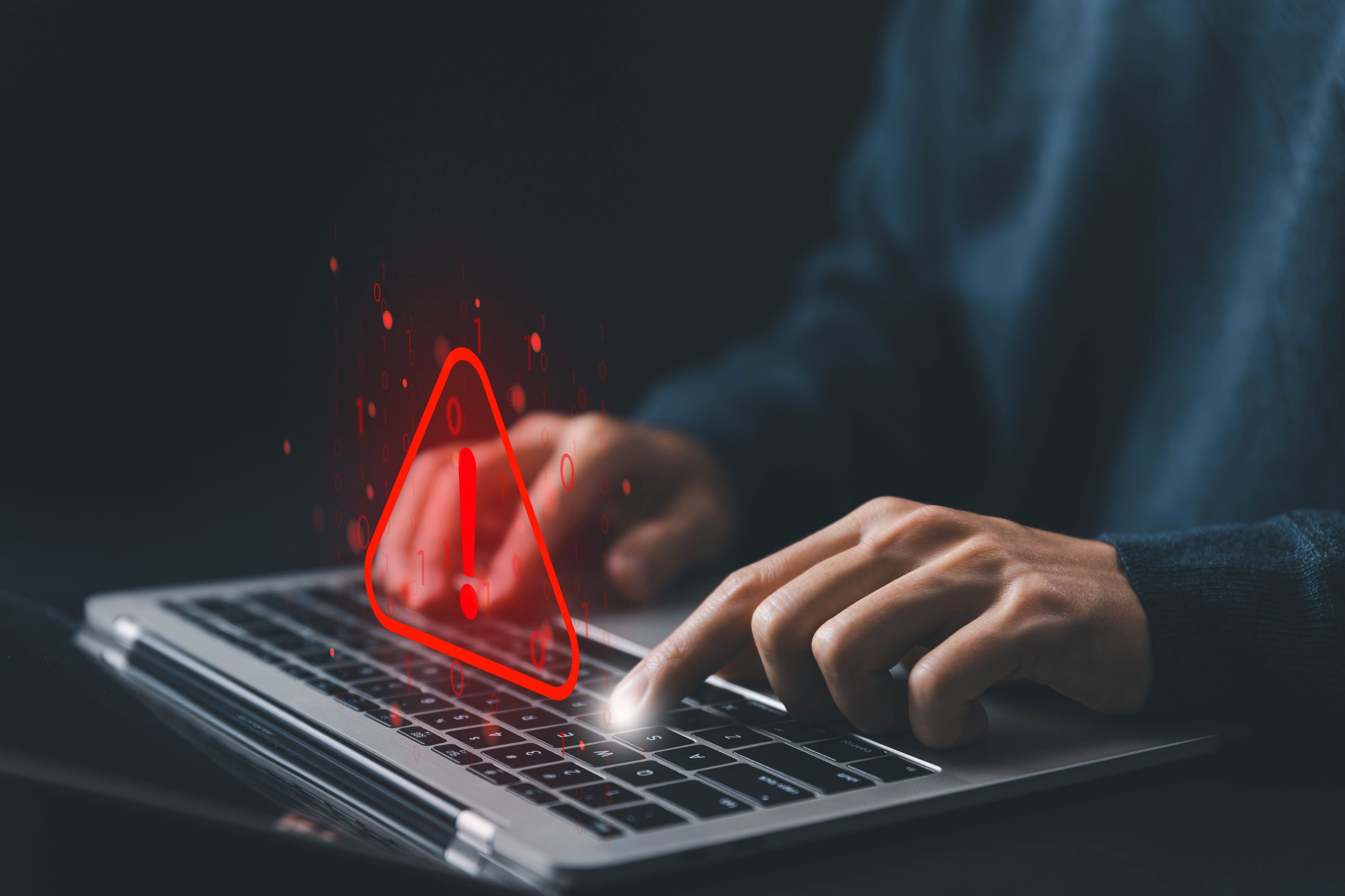 Homem usando um notebook, com um ícone digital flutuante de exclamação.