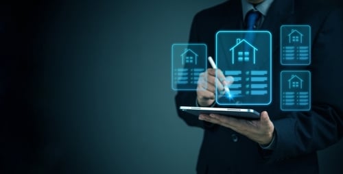 Profissional usando tablet com hologramas de imóveis simbolizando tecnologia no mercado imobiliário.