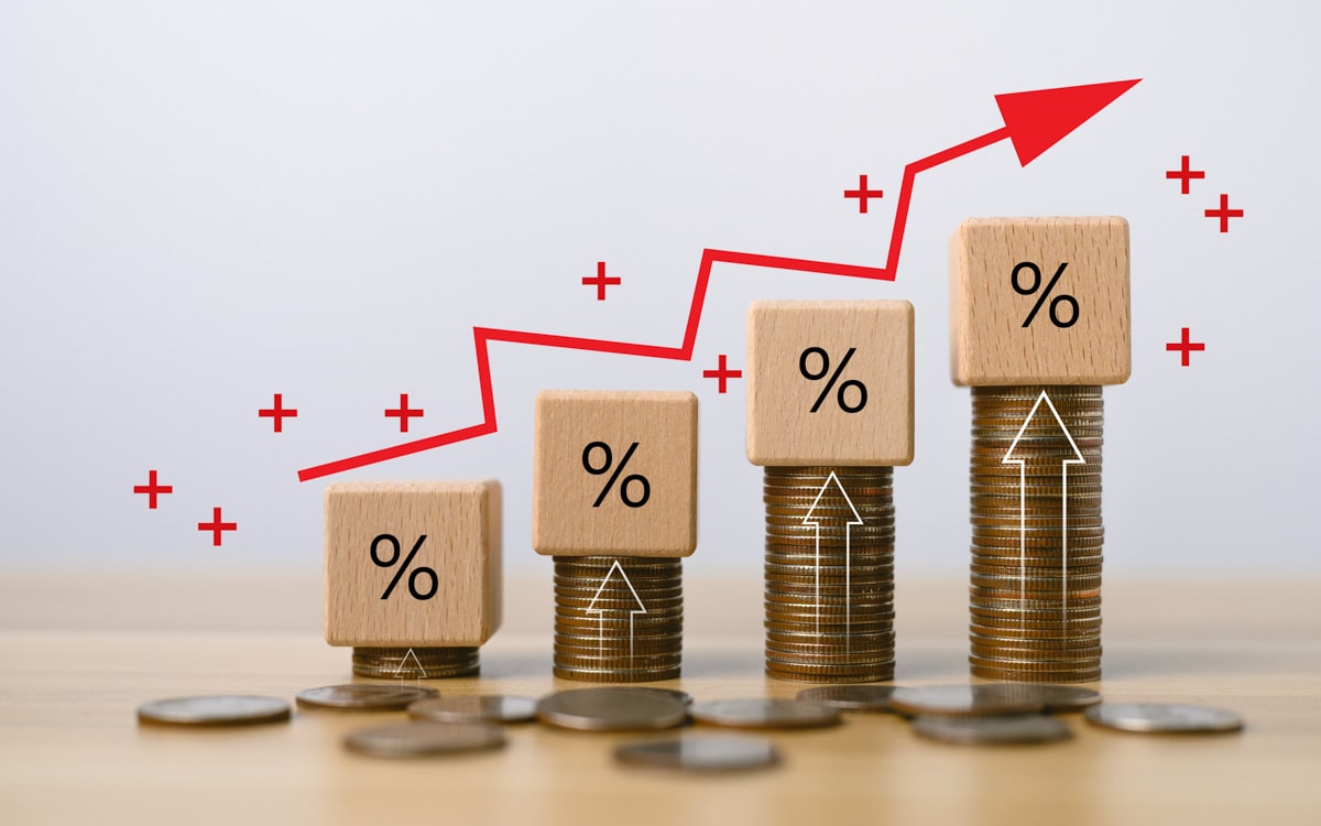 Conjunto de moedas empilhadas com figuras de porcentagem em dados de madeira, indicando crescimento financeiro.