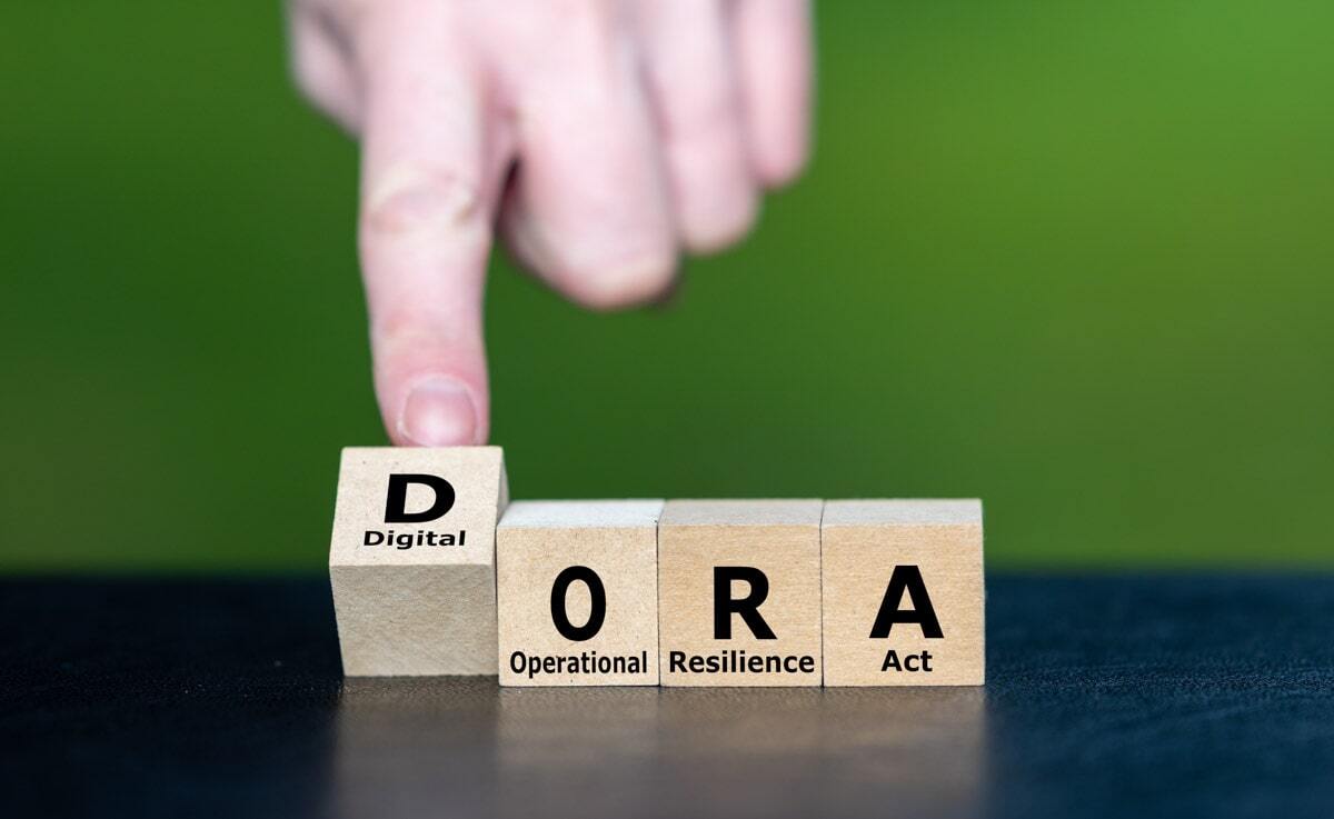 Mão masculina apontando para dados de madeira que juntos formam a palavra "DORA"