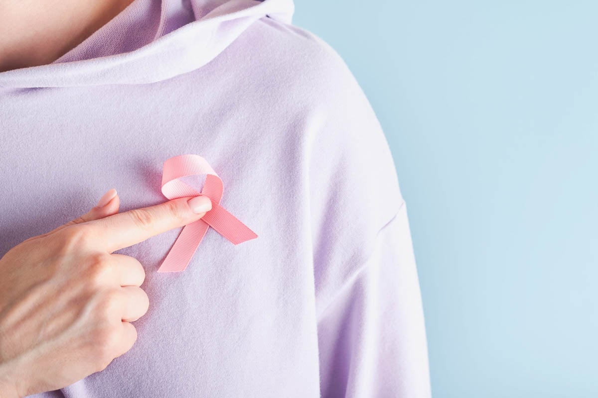 Mulher vestindo o laço rosa, representação da prevenção ao cancer de mama.