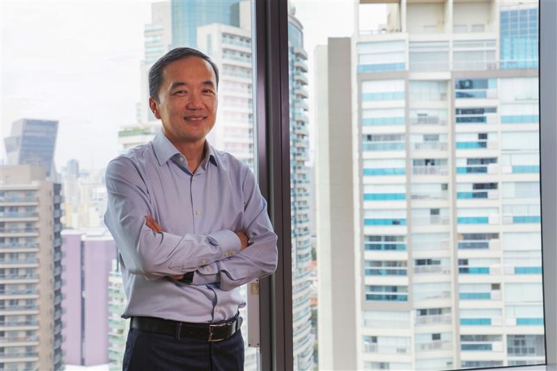 Pessoa em ambiente corporativo, em frente a janelas com vista urbana, representando liderança e compromisso da Allianz com sustentabilidade.