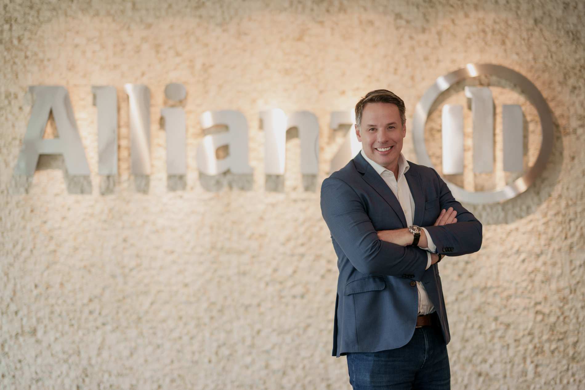 Diretor Nelson Veiga, em frente ao logotipo da Allianz, representando liderança e relacionamento com corretores.