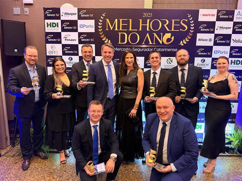 Grupo de profissionais reunidos em cerimônia de premiação, segurando troféus em frente a painel do prêmio Melhores do Ano do Sincor SC.