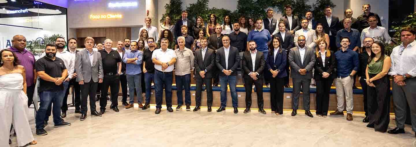 Grupo de pessoas em ambiente corporativo, posando para foto em um espaço com teto colorido e área verde.